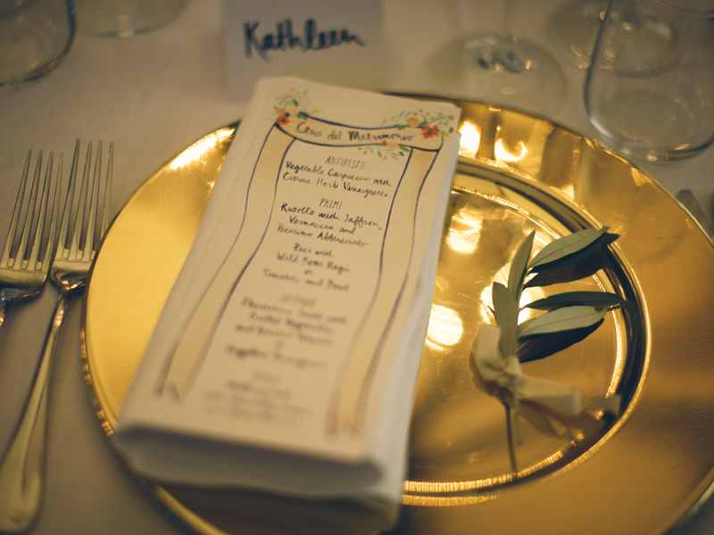  Above: a close up of the dinner menu framed by shiny gold chargers at each guest's seat. Image by  Lelia Scarfiotti.  